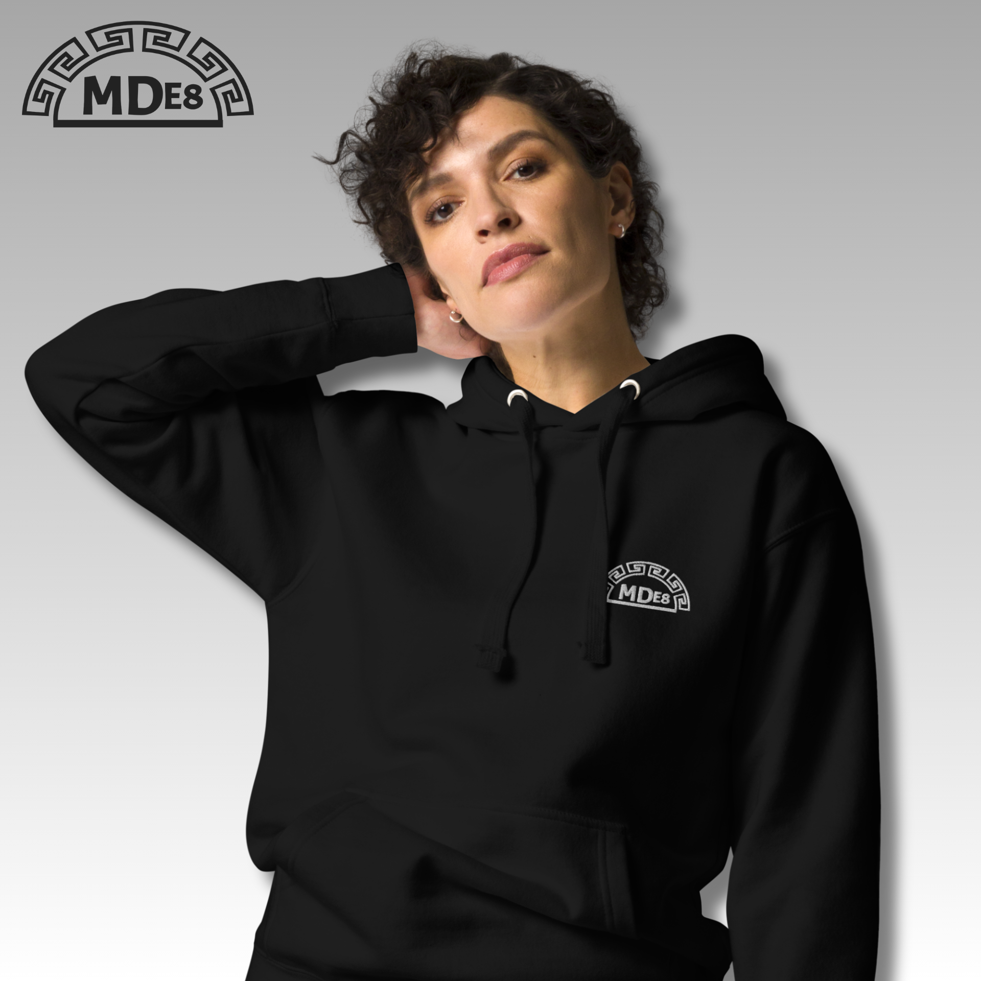 Person wearing a black hoodie with a logo on a white background