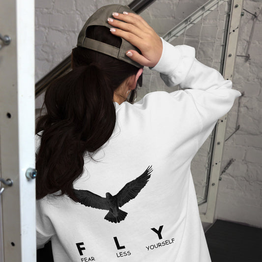 Person wearing a white hoodie with an eagle design and text, standing in a modern indoor setting.